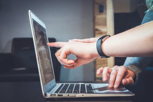 Two people pointing at a computer